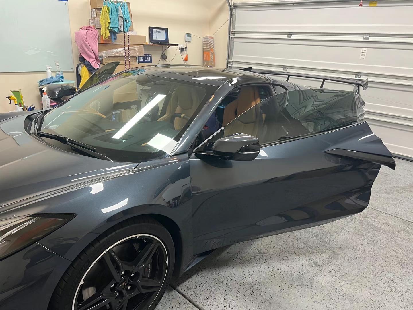 Dark gray Corvette with tinted windows and a door open in the shop