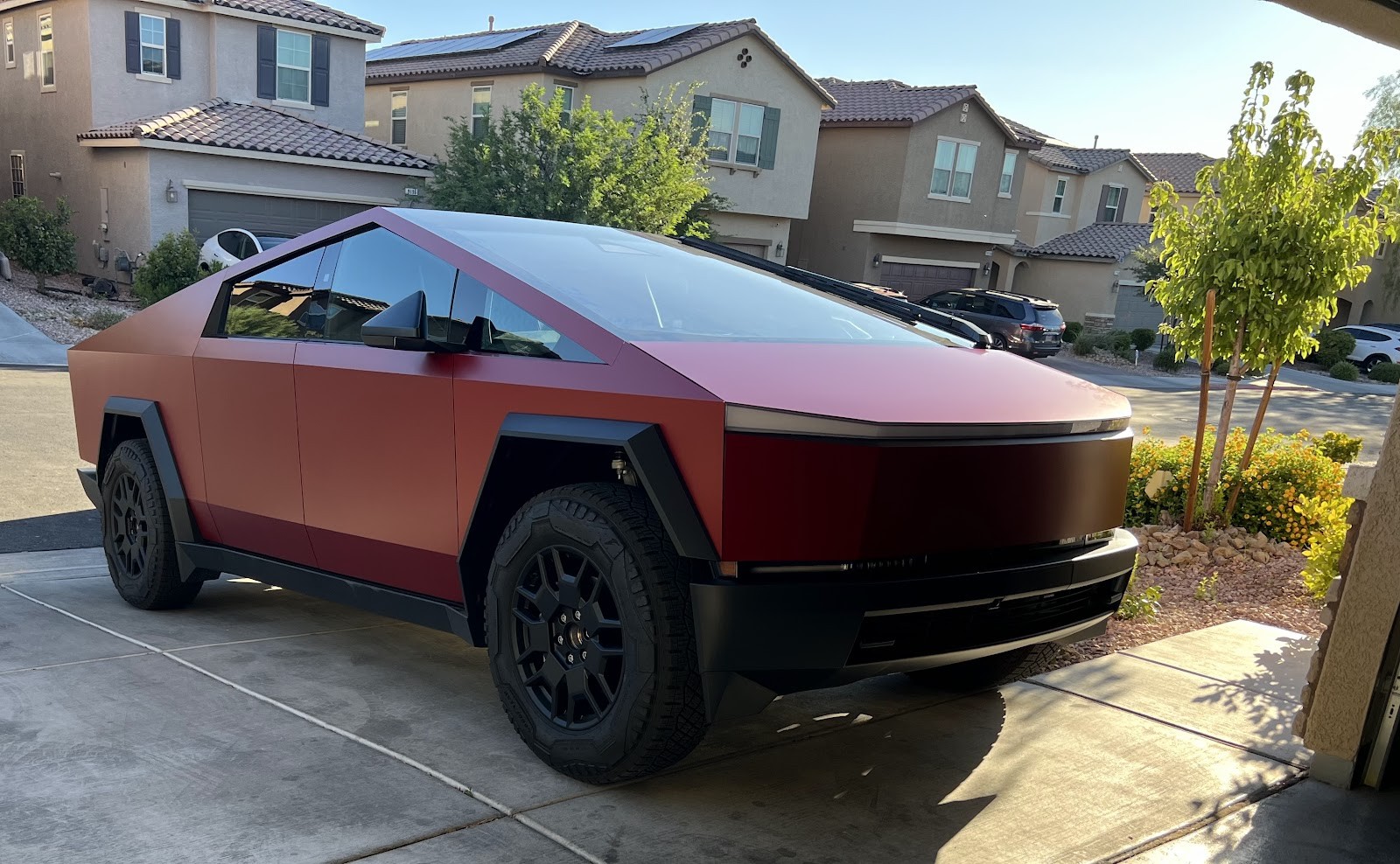 Red-wrapped Tesla Cybertruck parked in a residential driveway